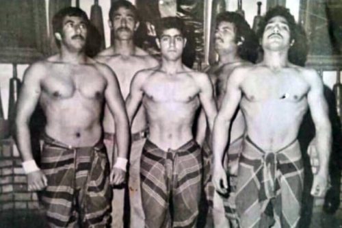 نفر وسط حاج قاسم در نوجوانی هنگام ورزش زورخانه‌ای